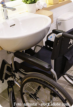 Waschbecken mit einem Rollstuhl davor.